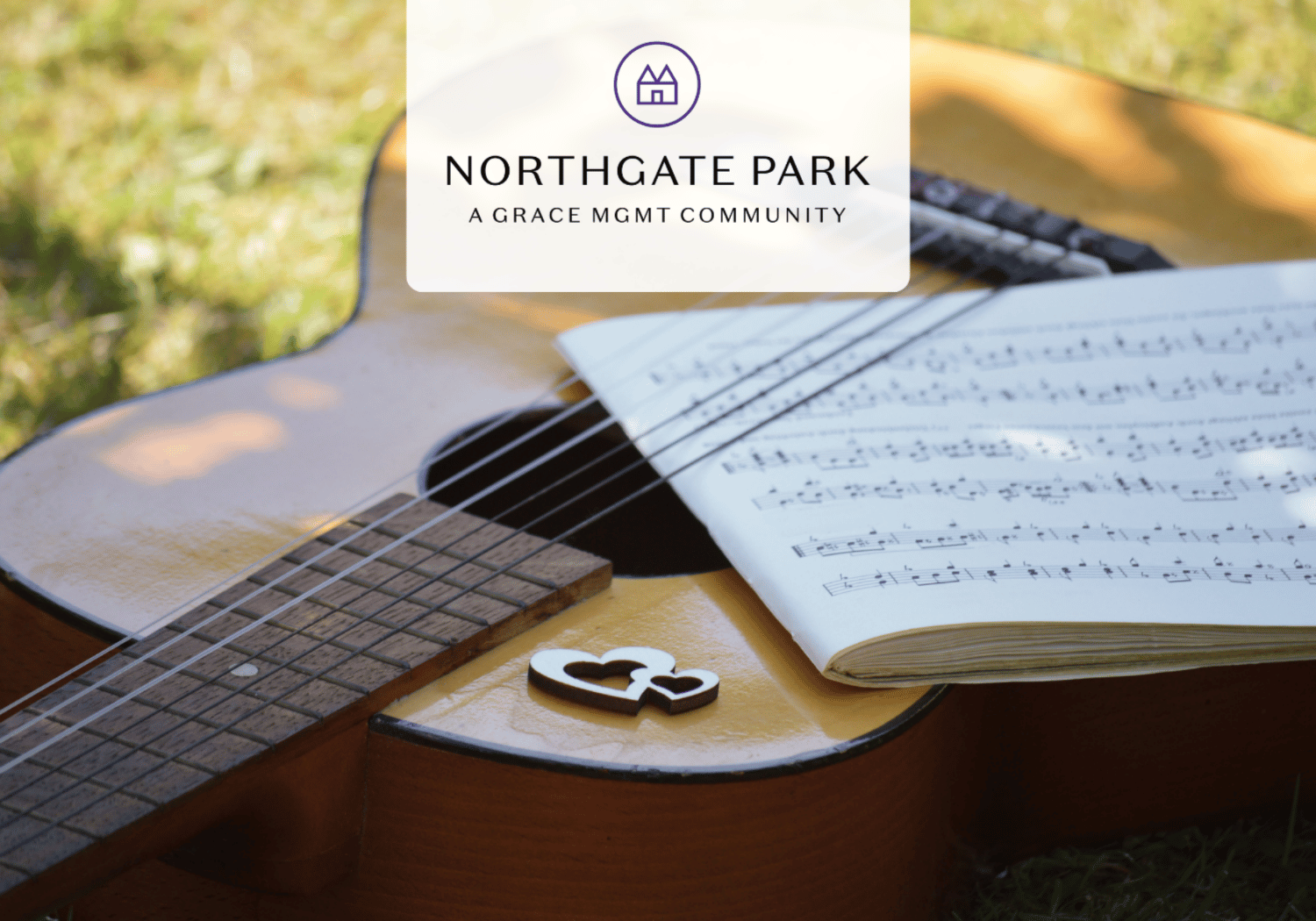 Acoustic guitar outdoors with open sheet music and a heart-shaped cutout on the body, overlaid with the Northgate Park branding.
